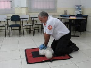 instrutor demonstrando como fazer compressões no torax, utilizando um manequim