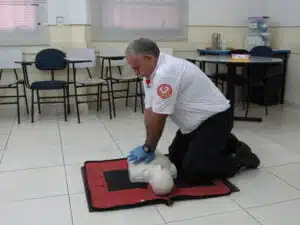 instrutor demonstrando como fazer compressões no torax, utilizando um manequim